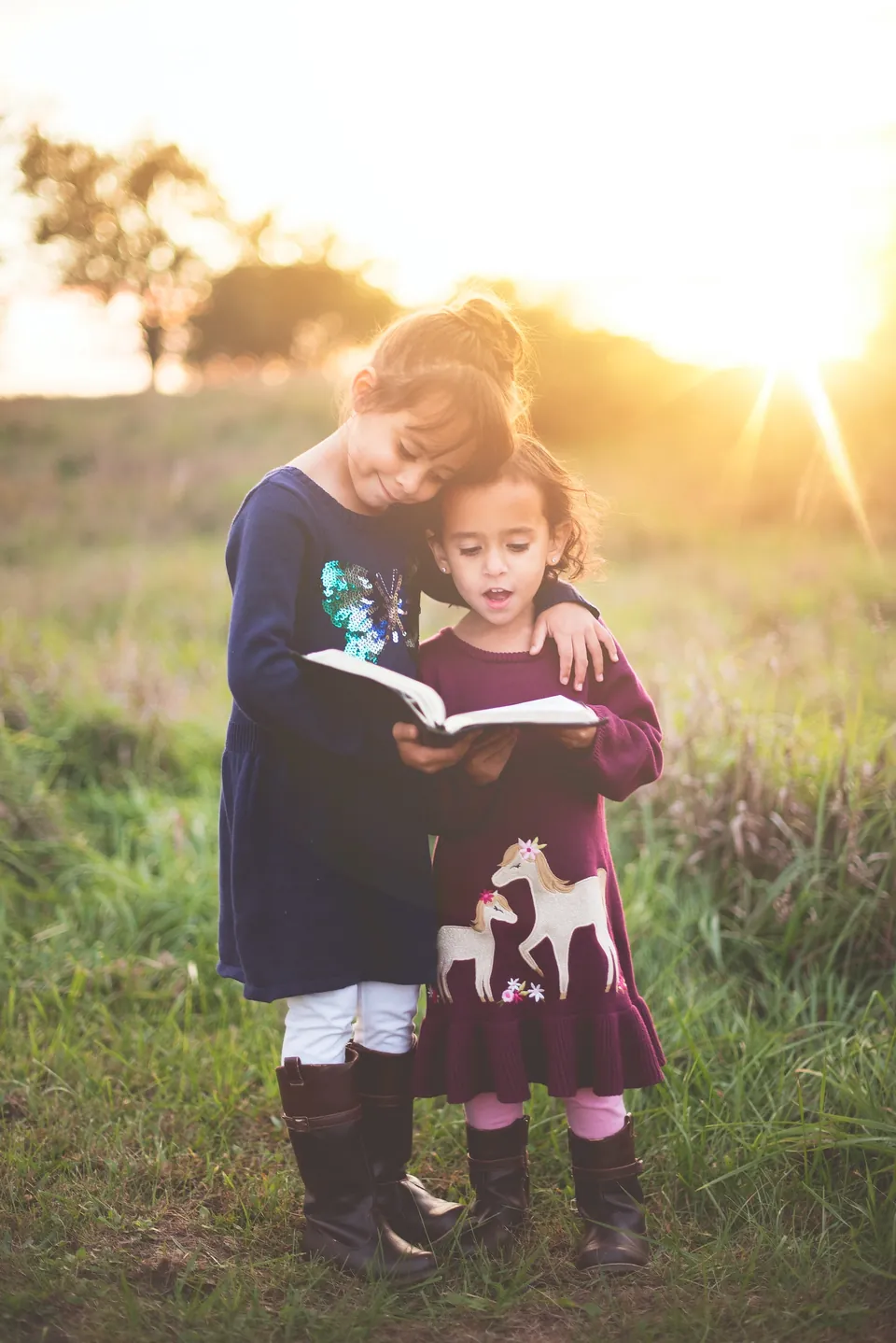 Two children reading a book together outdoors
